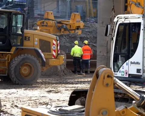 construction workers survey a site surrounded by heavy machinery and tools