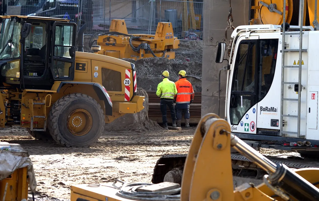 construction workers survey a site surrounded by heavy machinery and tools