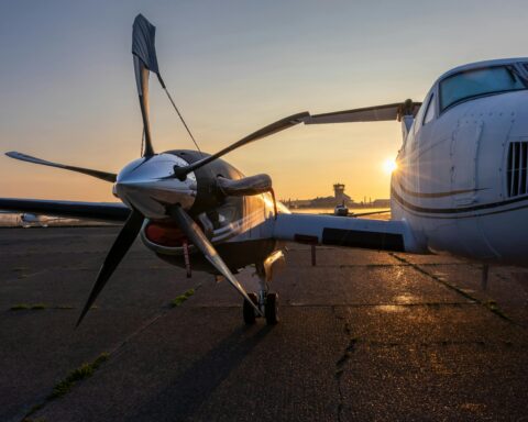 a closeup shot shows the rotor of a plane on the runway with a sunset in the background