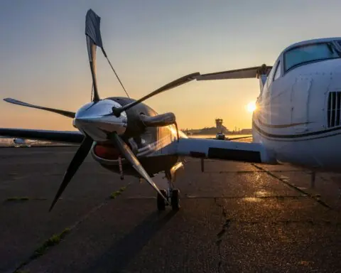 a closeup shot shows the rotor of a plane on the runway with a sunset in the background