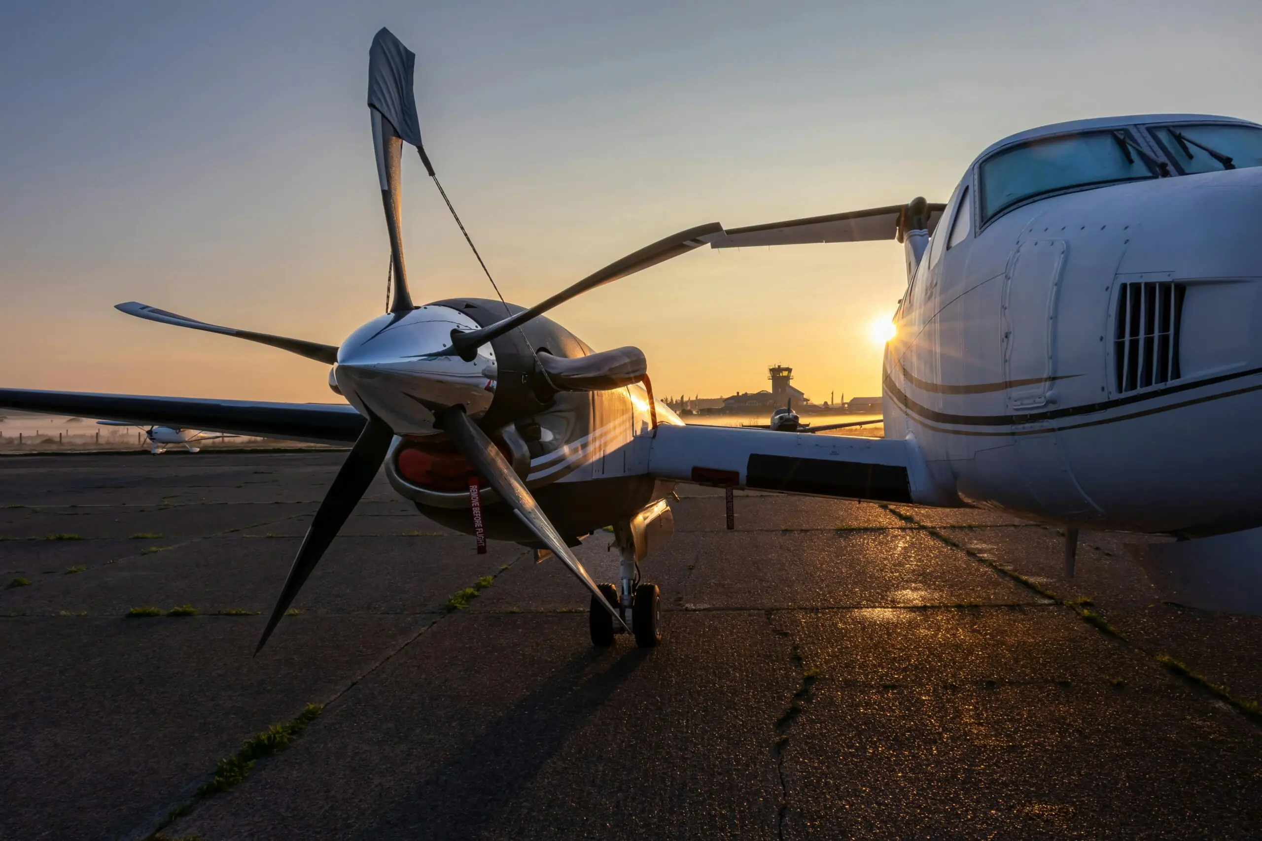 a closeup shot shows the rotor of a plane on the runway with a sunset in the background
