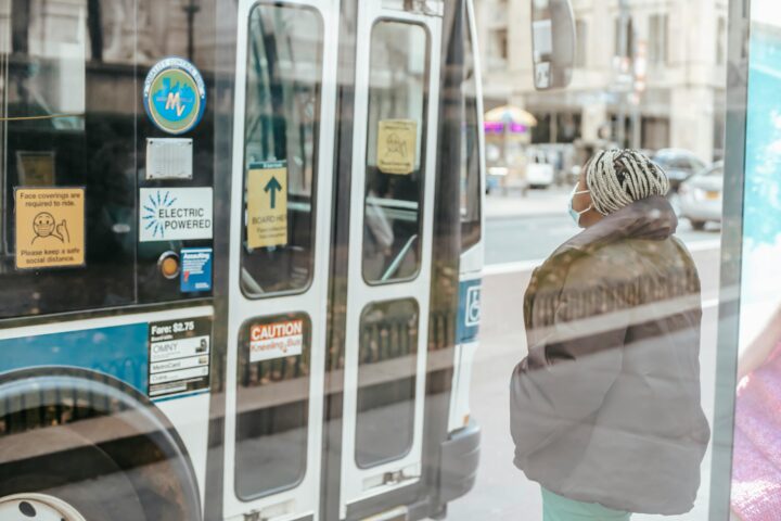 Masked lady waits for bus door to open.