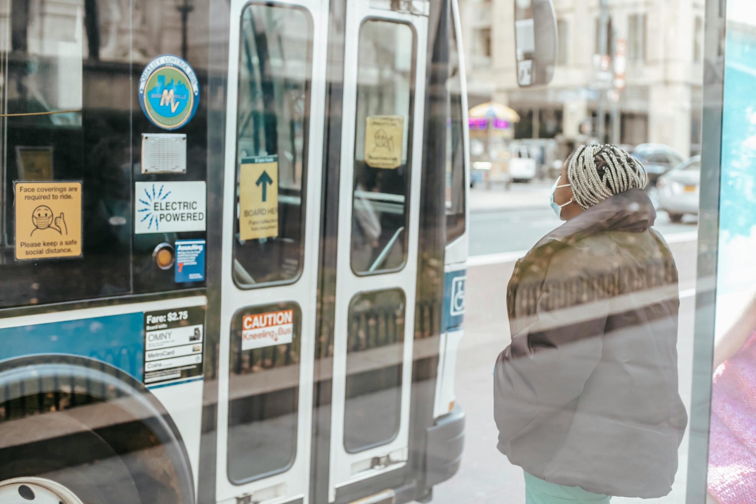 Masked lady waits for bus door to open.