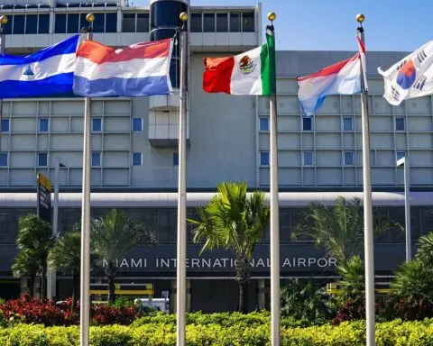 Six international flags sit on flag poles in front of the Miami International Airport building in Miami.
