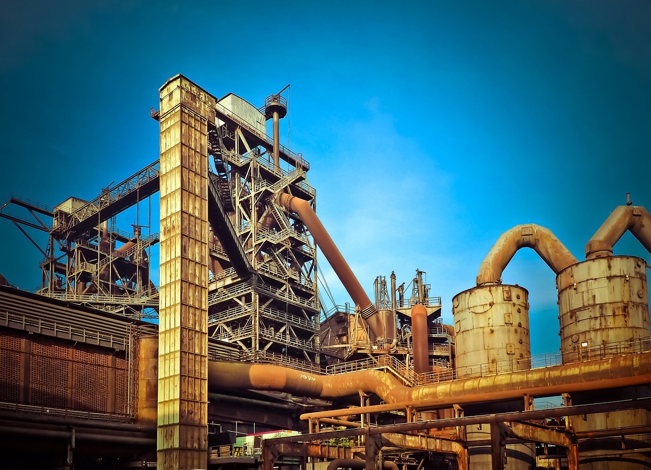 A rusty industrial building sits untouched amid a blue sky.