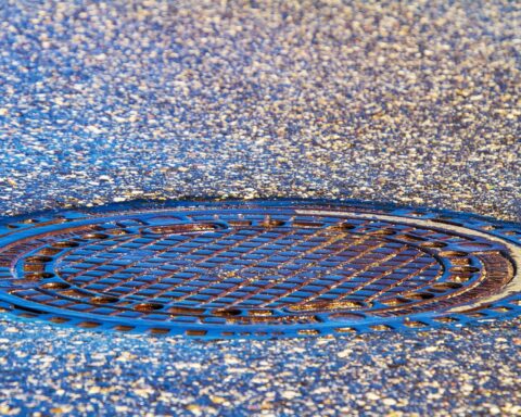 A sewer cover is photographed in the middle of a street.