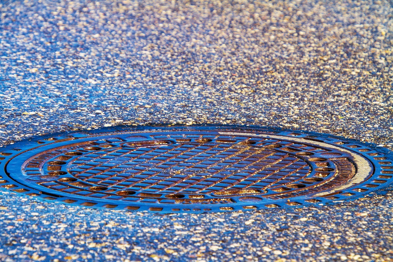A sewer cover is photographed in the middle of a street.