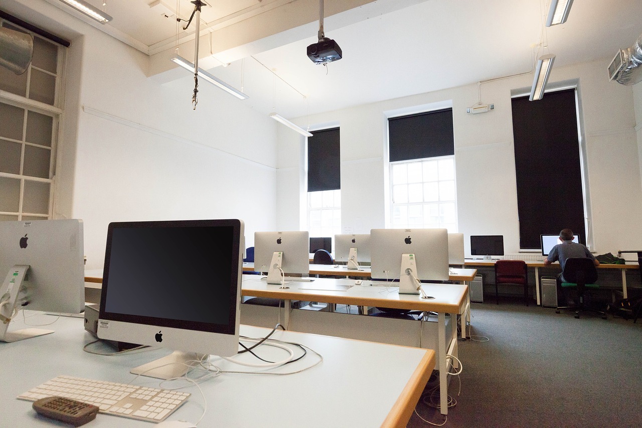 rows of computers at desks in a school classroom