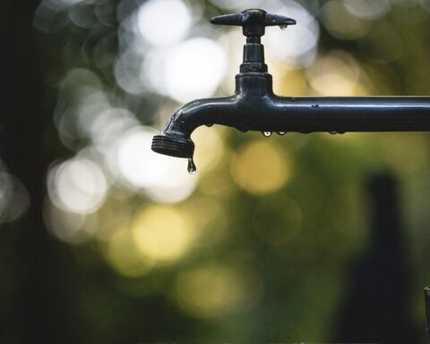 a faucet drips water in front of a blurry background
