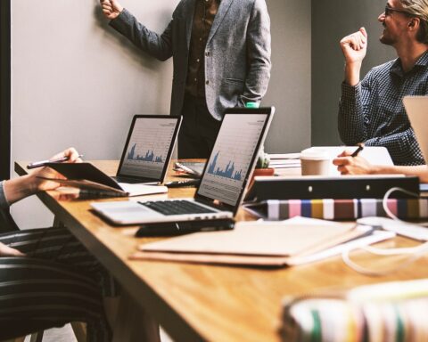 People in a business meeting discuss a project with laptops in an office