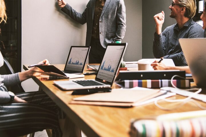 People in a business meeting discuss a project with laptops in an office