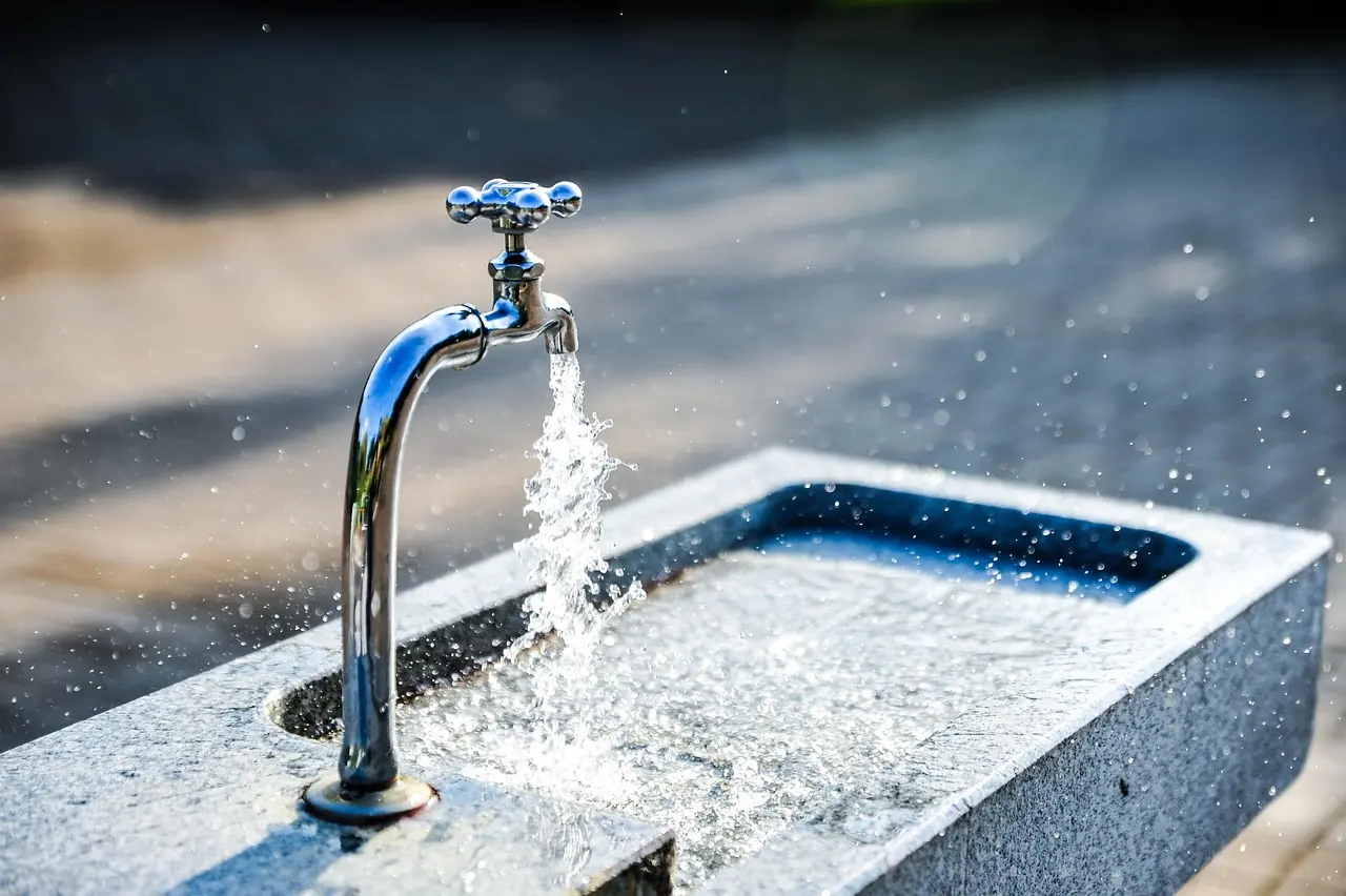 An outdoor water feature pours water into a fountain.