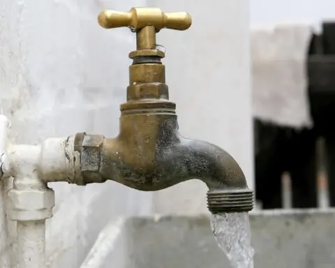 An outdoor faucet pours a stream of water into an attached sink.