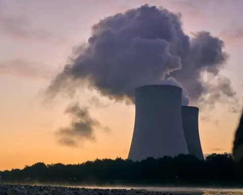 The image depicts a nuclear reactor in operations in front of a setting sun.