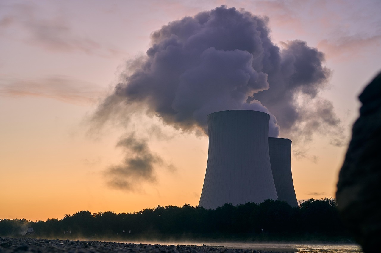 The image depicts a nuclear reactor in operations in front of a setting sun.