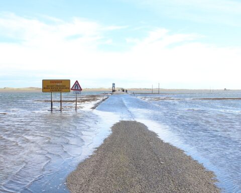 A sign notifies drivers of the potential of a washed out or flooded road as the road below is partially submerged in water.