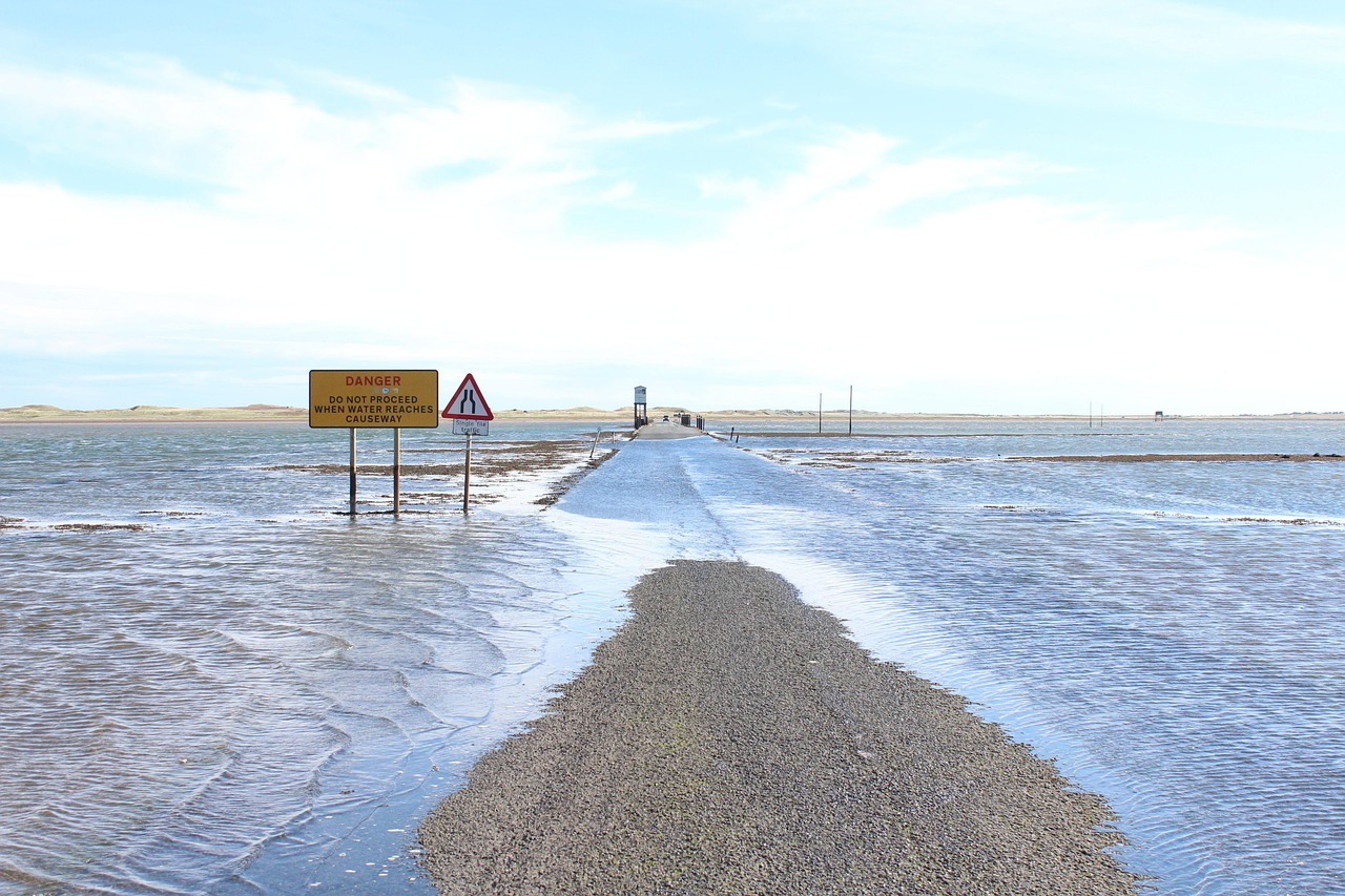 A sign notifies drivers of the potential of a washed out or flooded road as the road below is partially submerged in water.