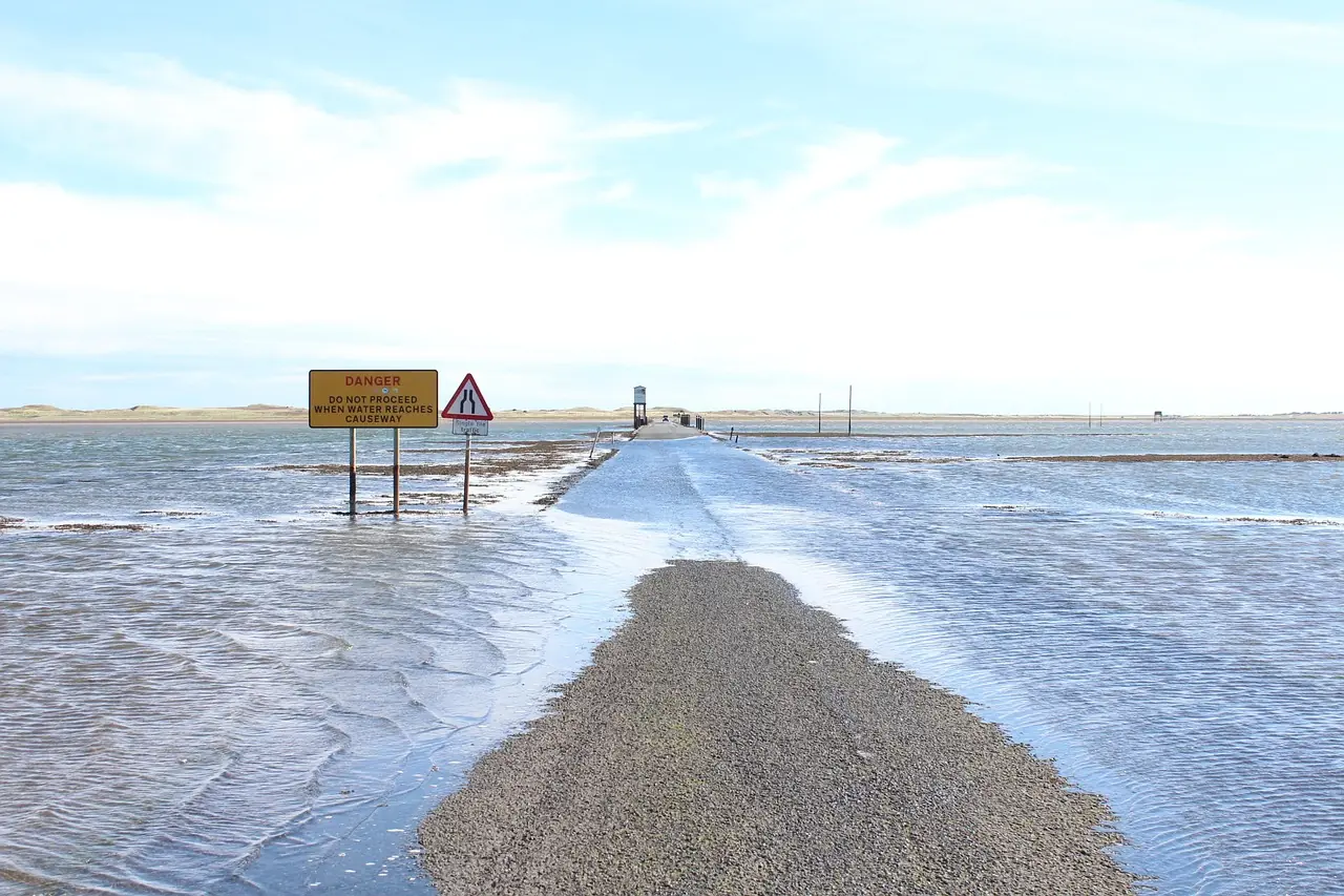 A sign notifies drivers of the potential of a washed out or flooded road as the road below is partially submerged in water.