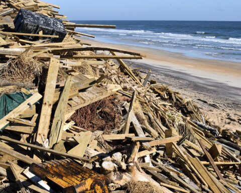 Garbage and debris are piled up alongside a beach concluding Hurricane Matthew.