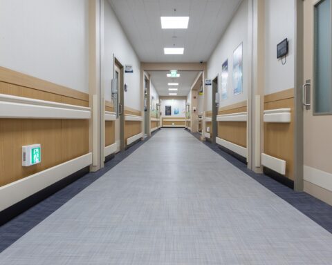 Bright overhead lights illuminate an empty hospital hallway.