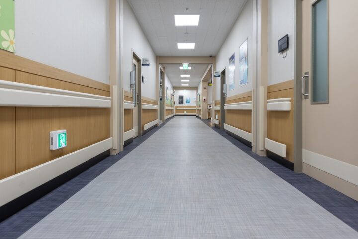 Bright overhead lights illuminate an empty hospital hallway.