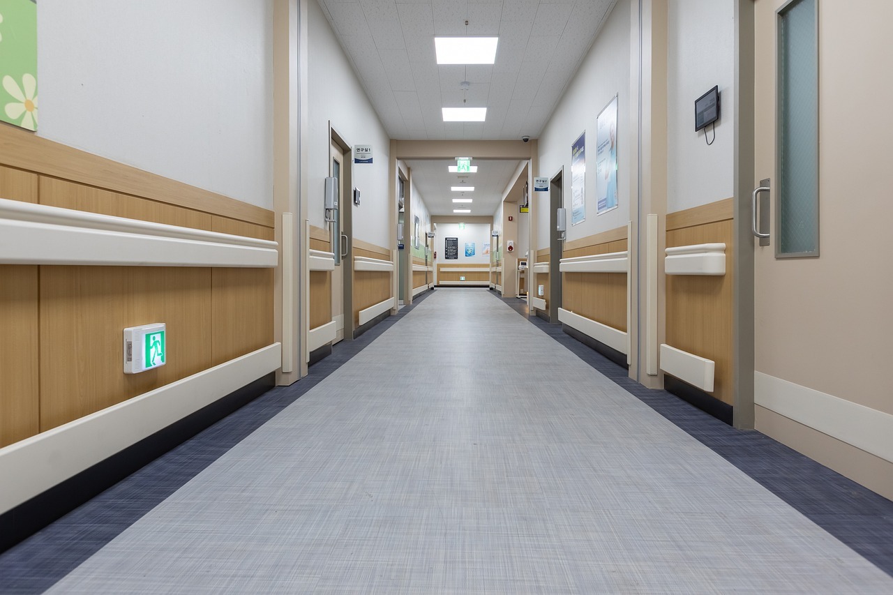 Bright overhead lights illuminate an empty hospital hallway.