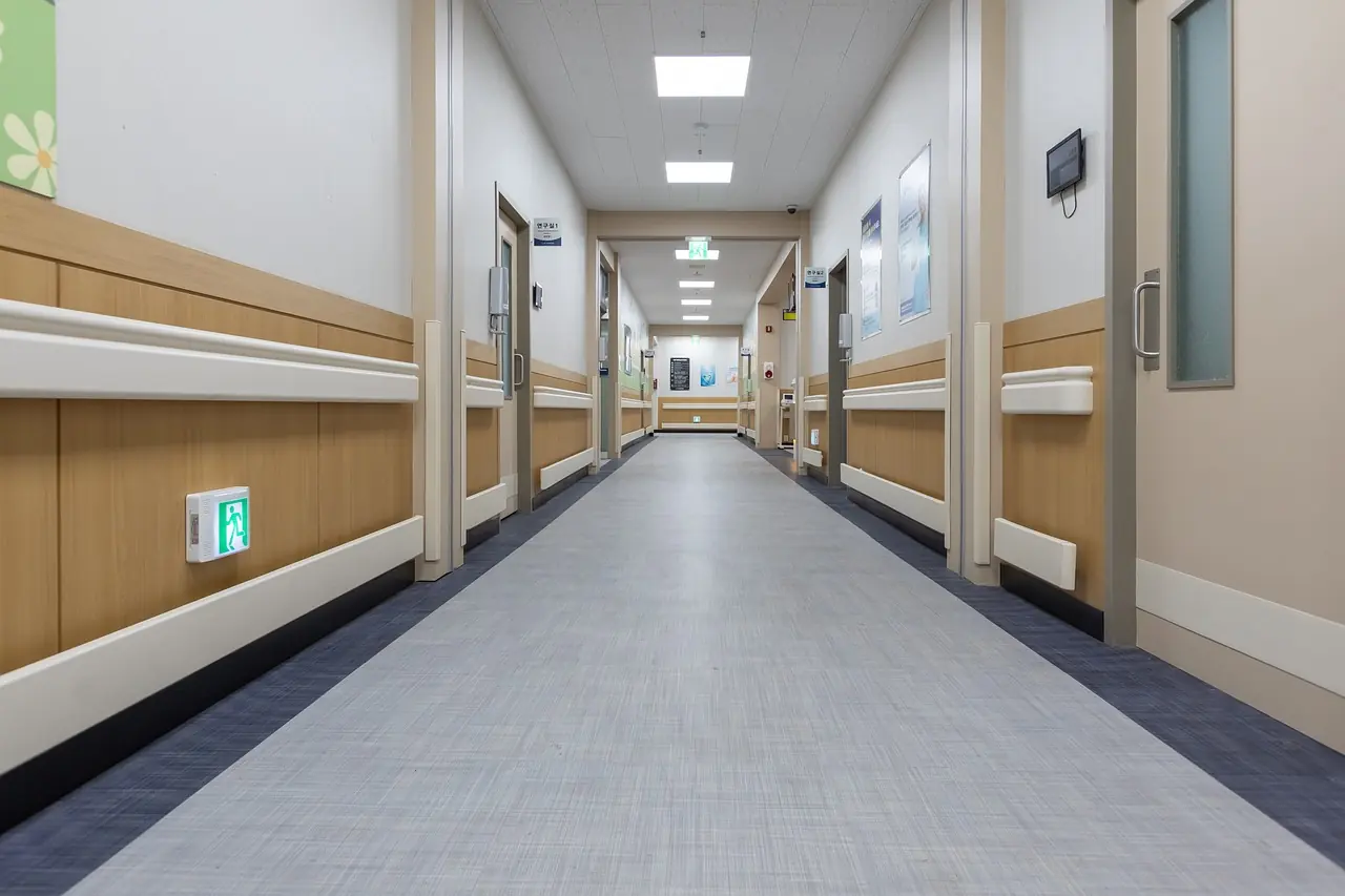 Bright overhead lights illuminate an empty hospital hallway.