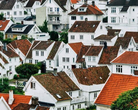 The image depicts a view above a neighborhood full of white houses and reddish roofs.