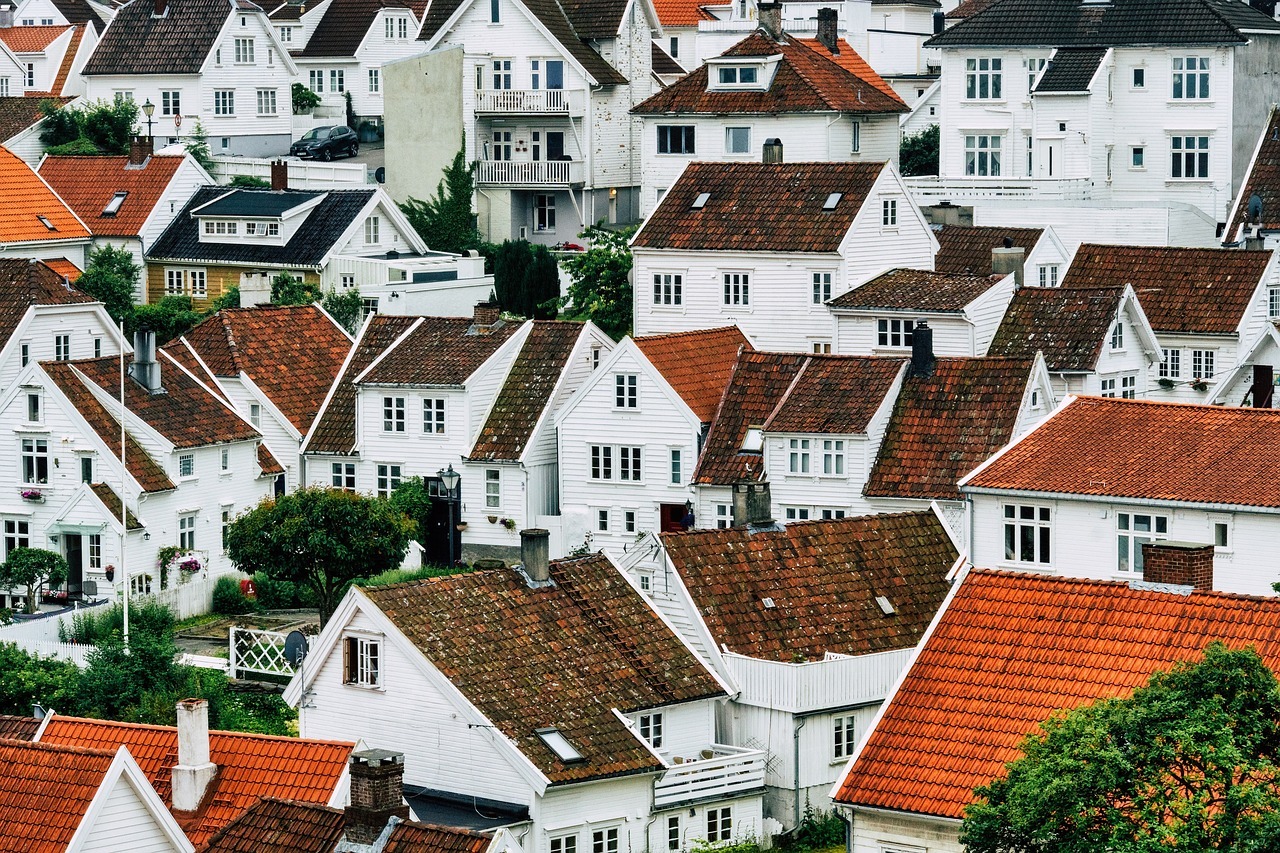 The image depicts a view above a neighborhood full of white houses and reddish roofs.