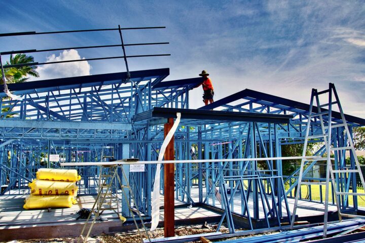 Construction workers work on a housing development held up by blue structuring.