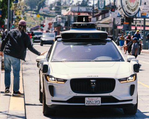 An autonomous vehicle and a prospective passenger on a street in California.