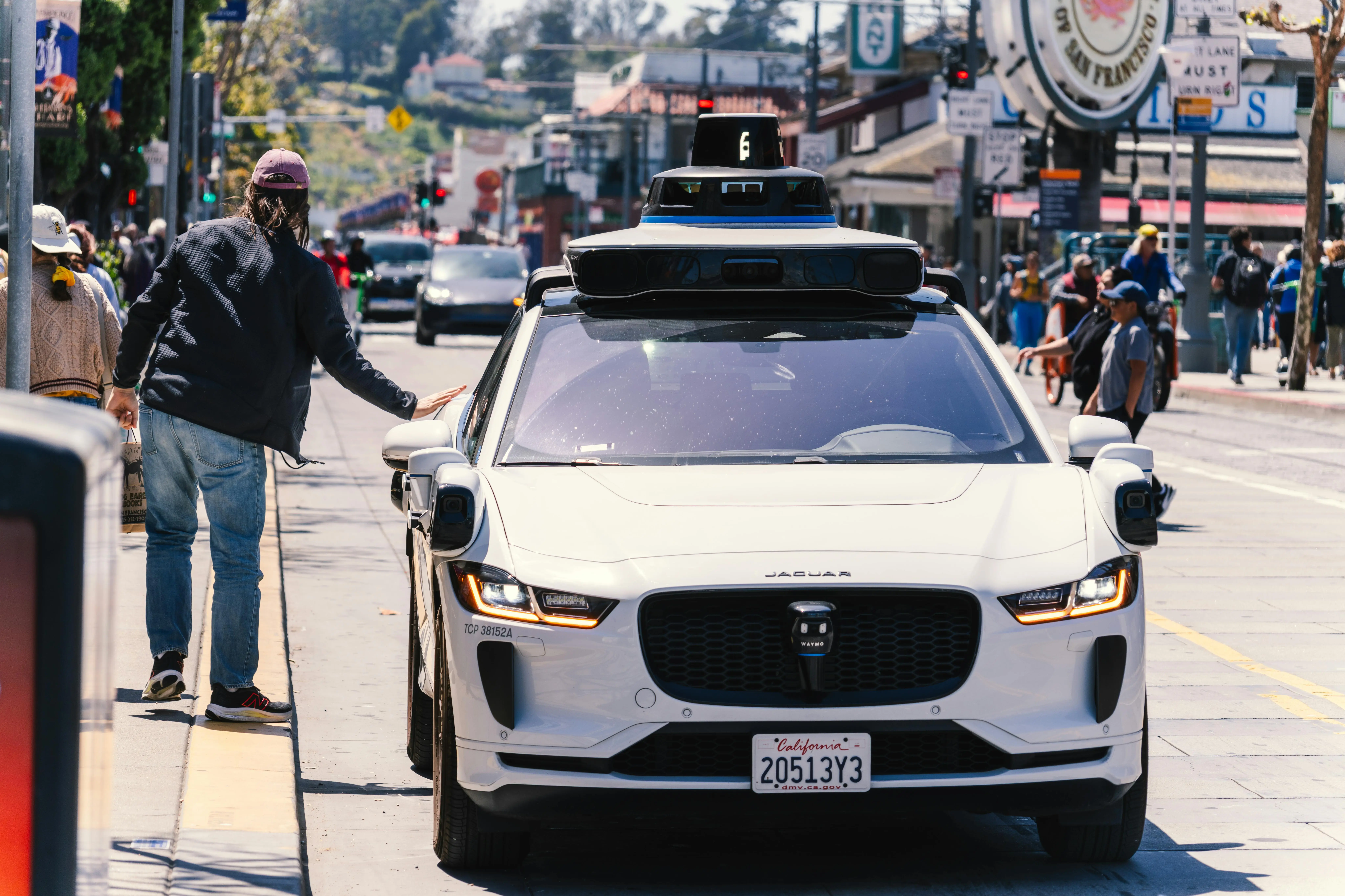 An autonomous vehicle and a prospective passenger on a street in California.