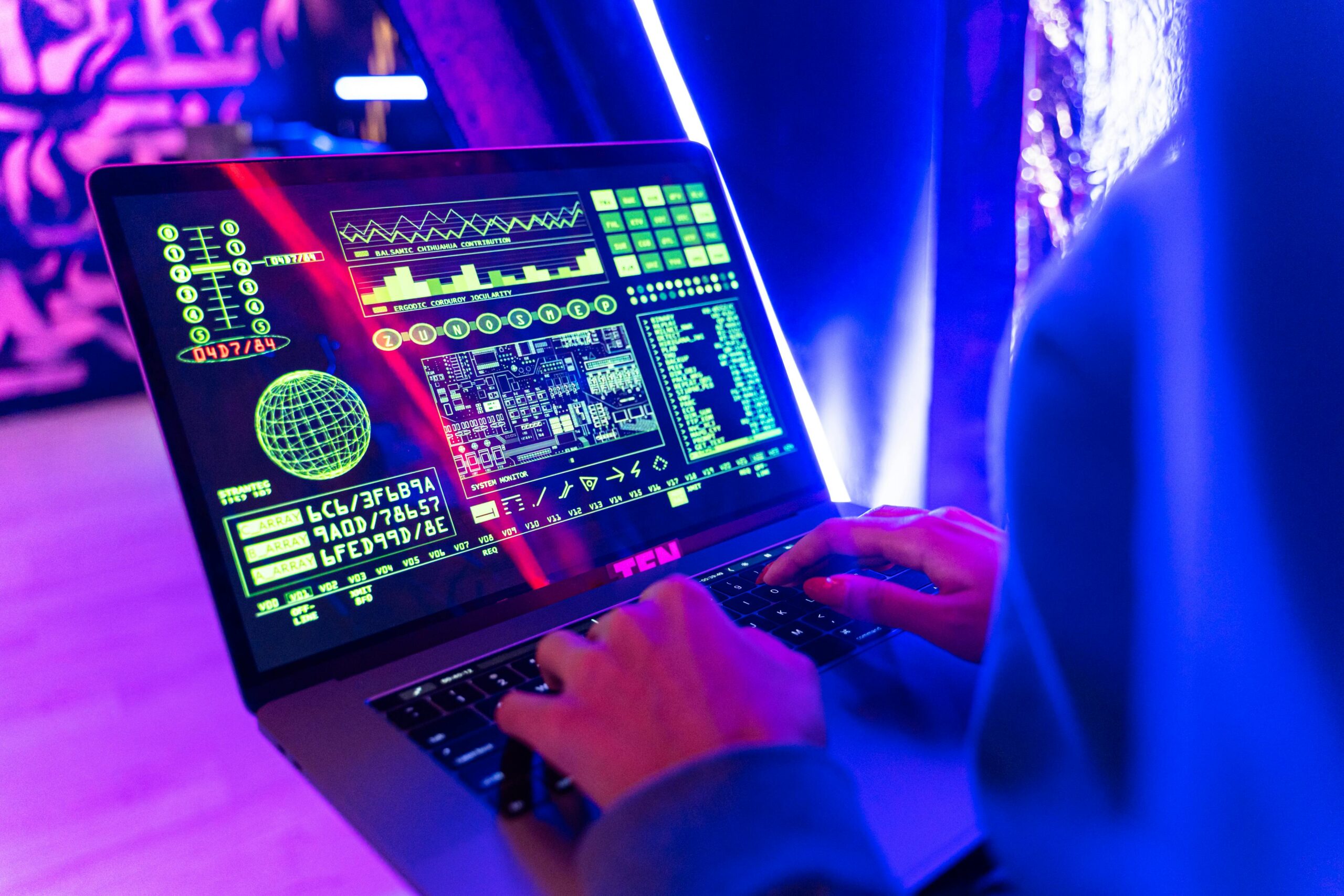 A person uses a computer with various online tools on-screen with neon blue and purple lighting.