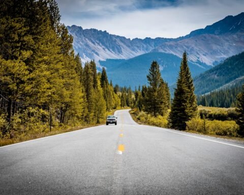 A car in the middle of a scenic Colorado road in the Rocky Mountains.
