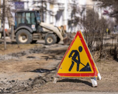 A construction sign depicting a worker shoveling in front of a construction site with vehicles.