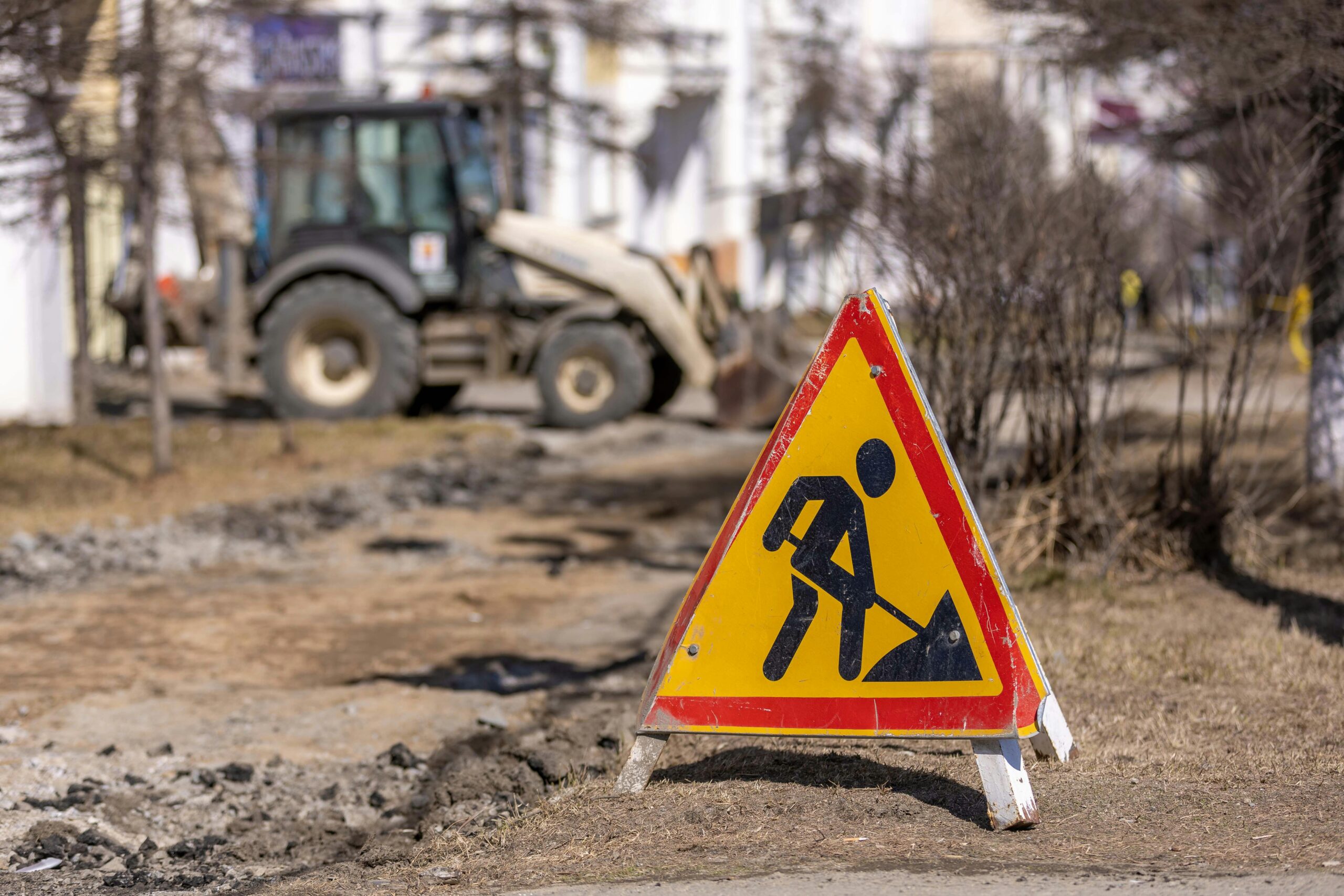 A construction sign depicting a worker shoveling in front of a construction site with vehicles.