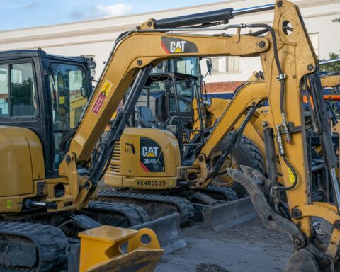 Several construction vehicles sit near one another on a construction site.