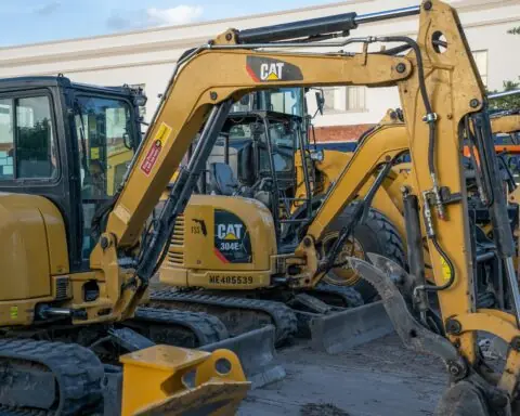 Several construction vehicles sit near one another on a construction site.