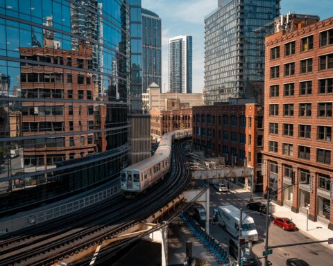 An intersection with an elevated train track and cars beneath is photographed from a building top in Chicago.