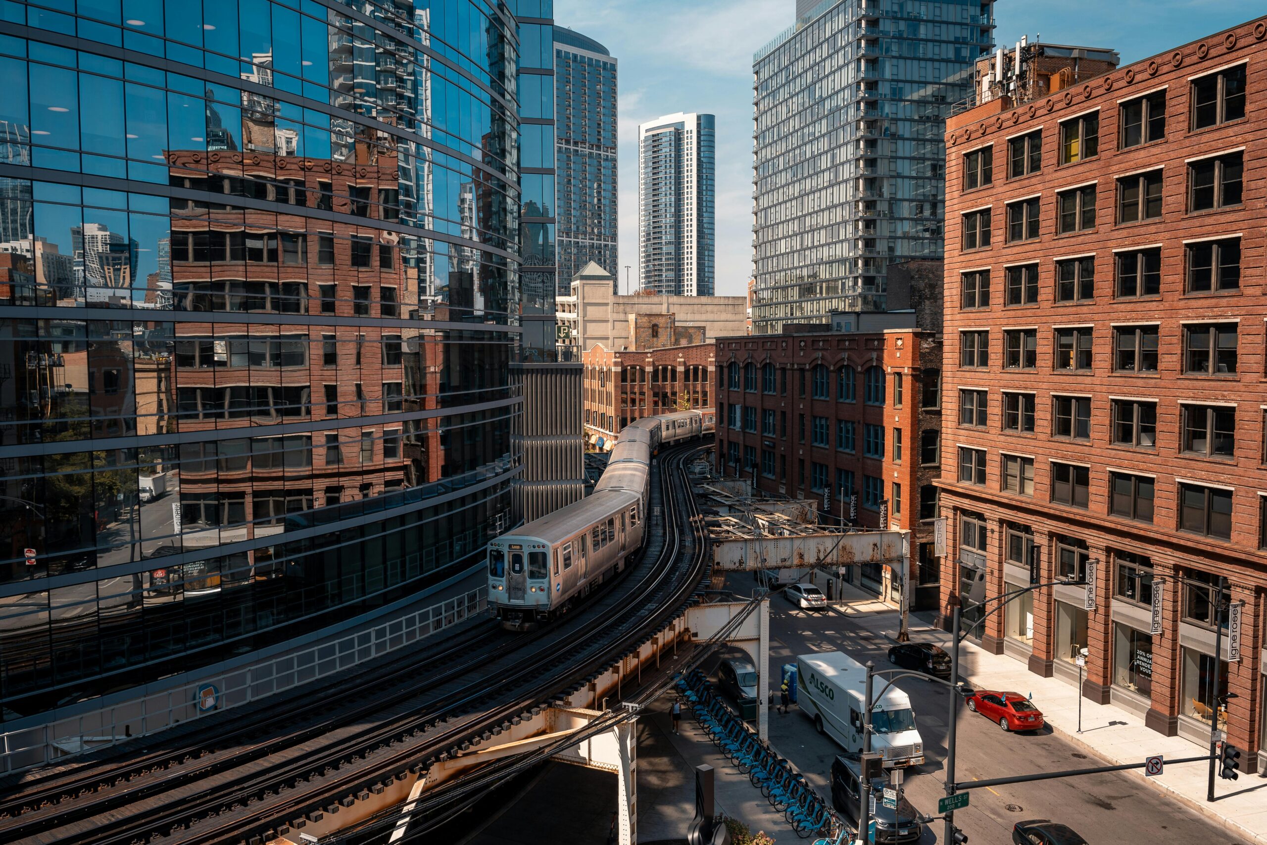 An intersection with an elevated train track and cars beneath is photographed from a building top in Chicago.