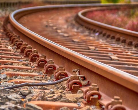 A rusty set of railroad tracks along gravel.