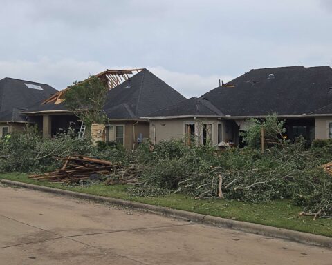 Disaster-damaged homes with broken trees and debris in Cypress near Houston, Texas.