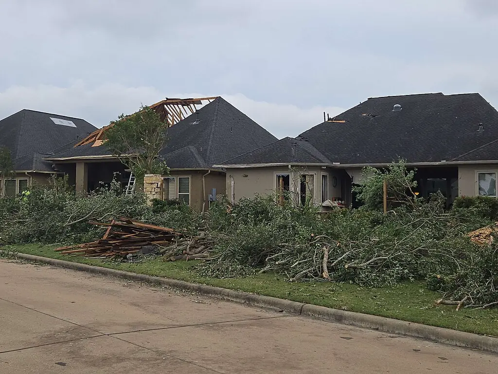 Disaster-damaged homes with broken trees and debris in Cypress near Houston, Texas.