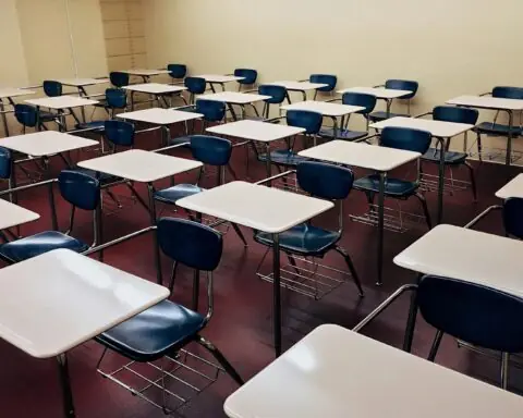 A classroom full of empty chairs and desks for students.
