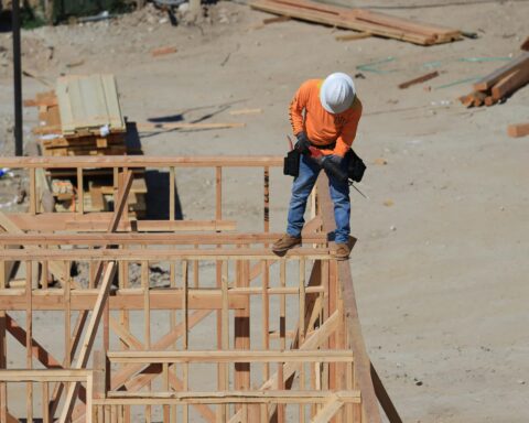 A construction worker stands atop the frames of a development and construction site beneath him.