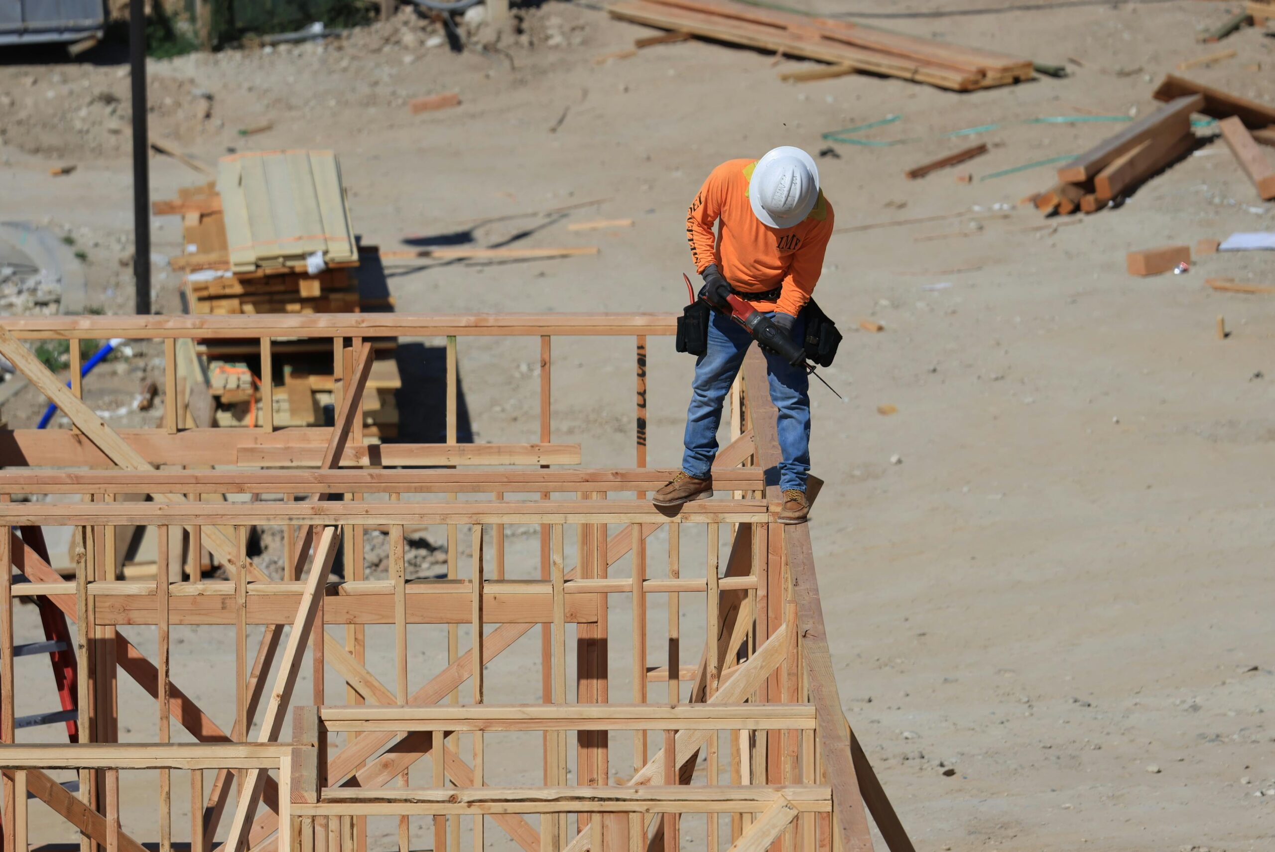 A construction worker stands atop the frames of a development and construction site beneath him.