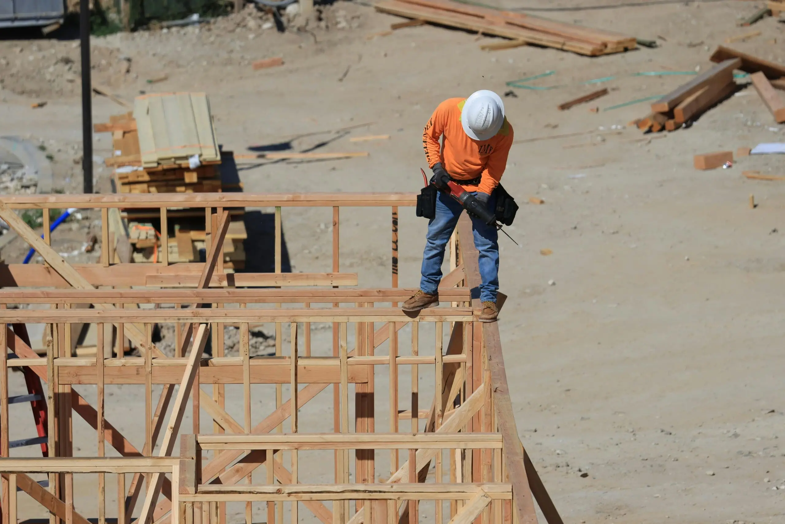 A construction worker stands atop the frames of a development and construction site beneath him.