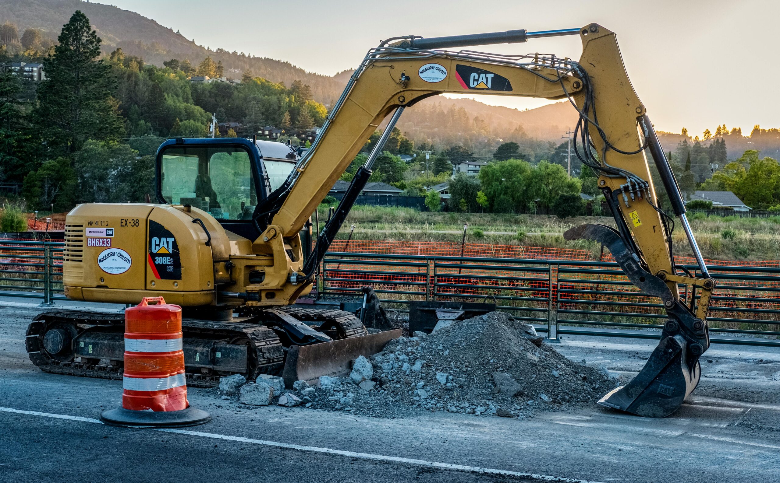 An excavator pulls rumble alongside a concrete road.