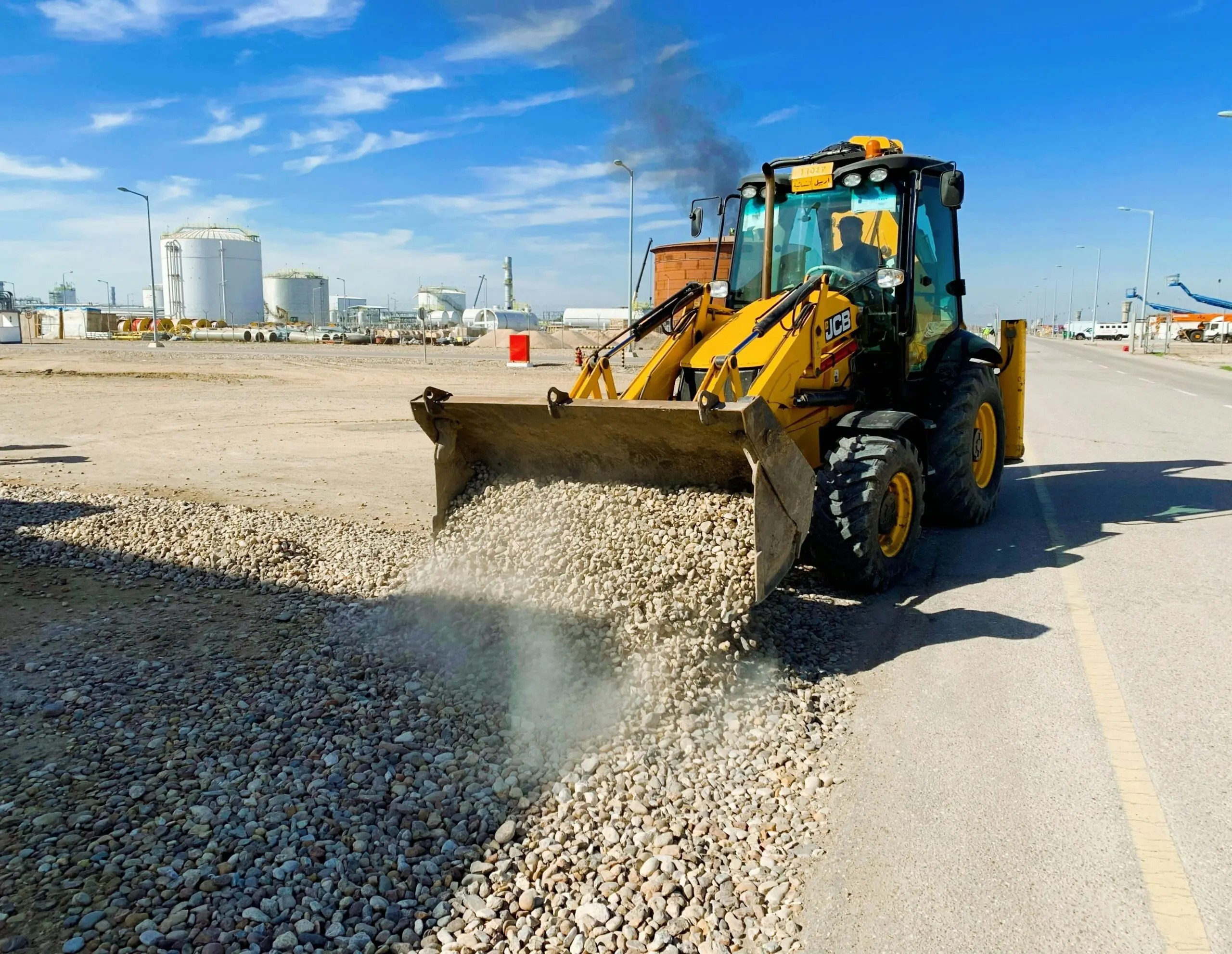 An excavator offloads rubble near a road.