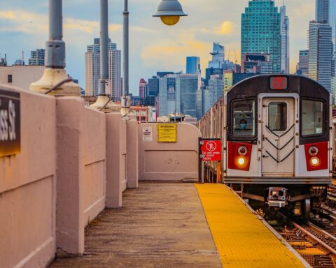 An MTA train in New York City approaches a pedestrian platform.